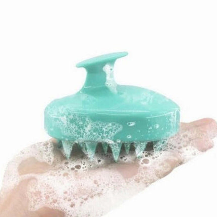 Turquoise scalp massager with soap suds on a hand against a white background